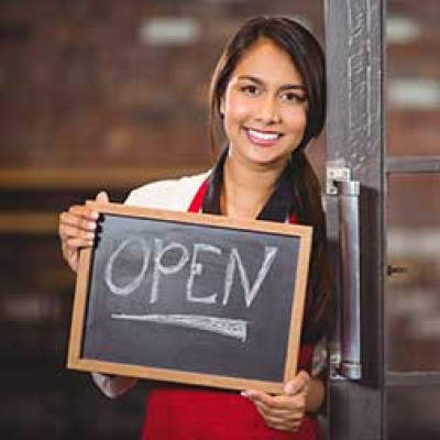 A women holding a chalkboard sign that says "Open"