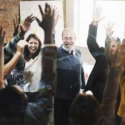 A group of office workers cheering with hands raised