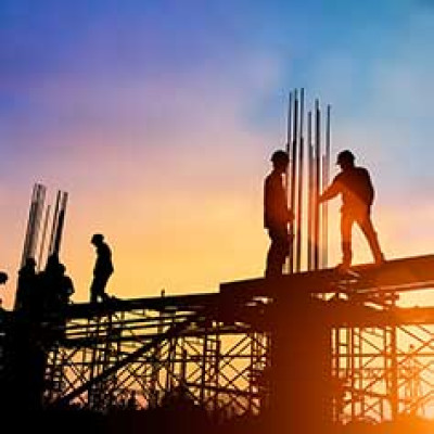 Silhouettes of men standing on scaffolding with a sunset in the background